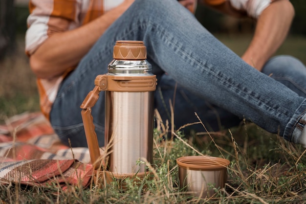 Free photo side view of man relaxing outdoors with thermos