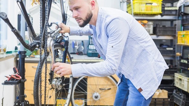 Free photo side view of a man repairing bicycle