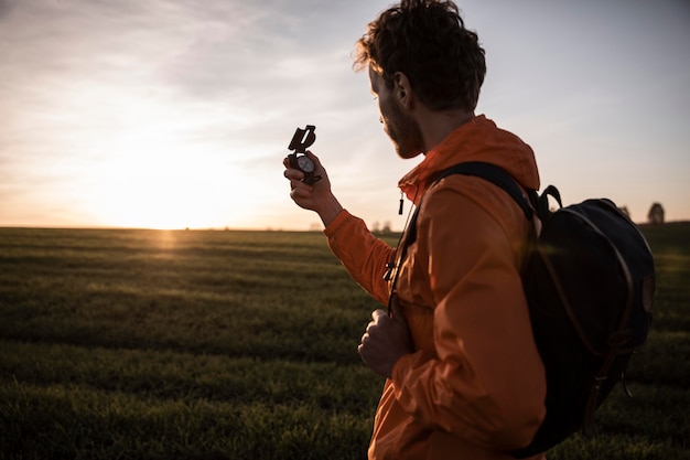 Side view of man on a road trip admiring the view while holding compass