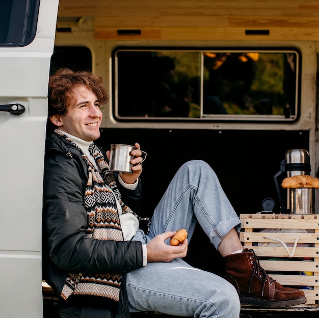 Free photo side view man sitting in a van drinking his coffee