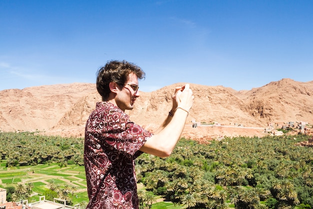 Side view of a man taking picture of oasis