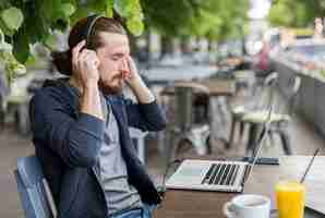 Free photo side view of man at terrace with headphones and laptop