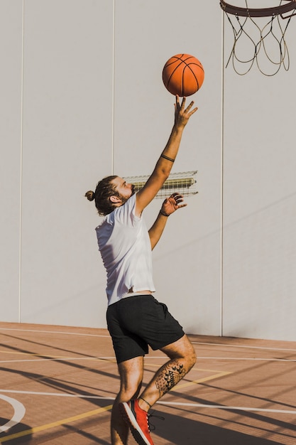 Side view of a man throwing basketball in hoop