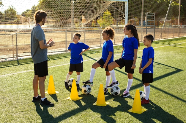 Side view man training kids playing football