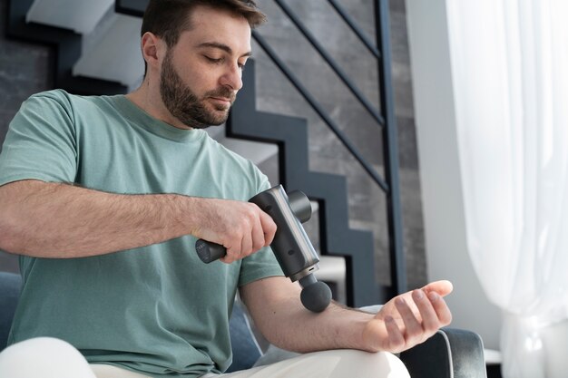 Side view man using massage gun