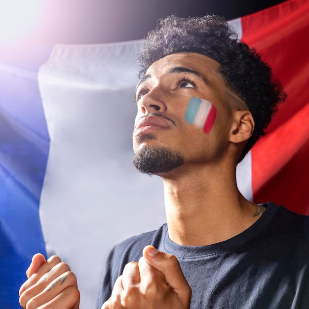 Free photo side view of man with french flag looking up and holding fists together