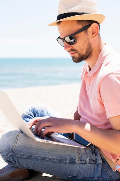 Side view of man with laptop at the beach