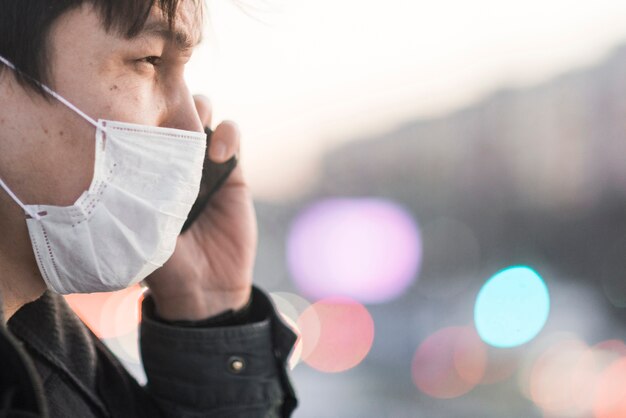 Side view of man with medical mask talking on the phone