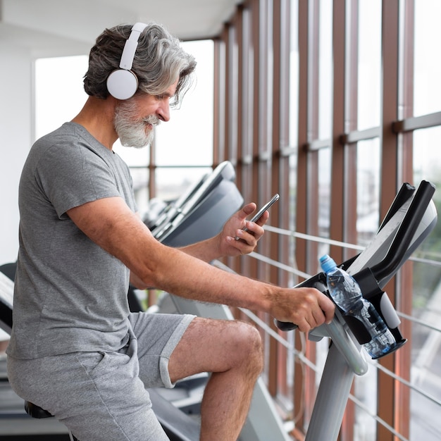 Side view man with phone on bicycle