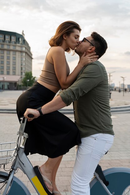 Side view man and woman kissing on bicycle