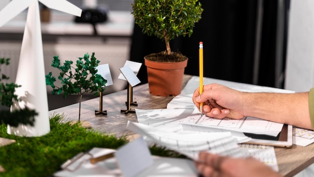 Free photo side view of man working on an eco-friendly wind power project with paper plans