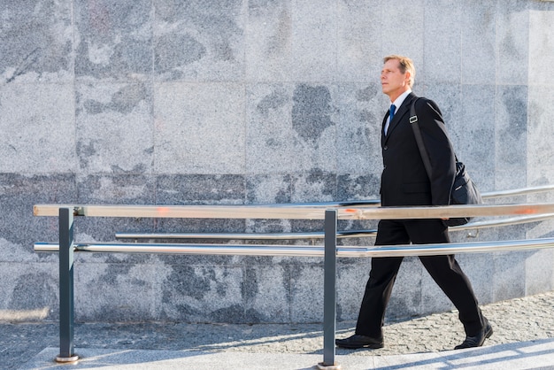 Free photo side view of a mature man walking near railing