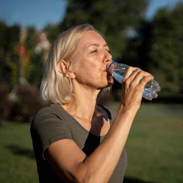 Side view of mature woman drinking water outdoors