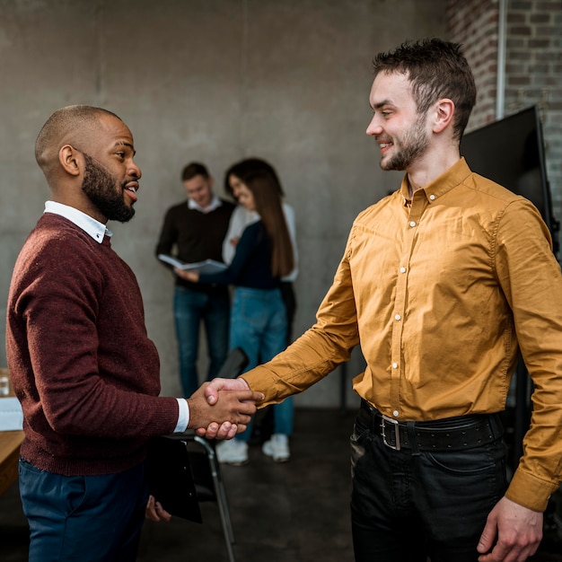 Free photo side view of men handshaking in agreement after a meeting