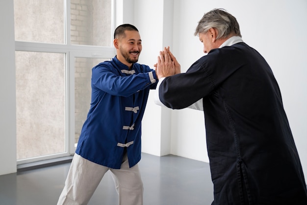 Free photo side view men practicing tai chi together