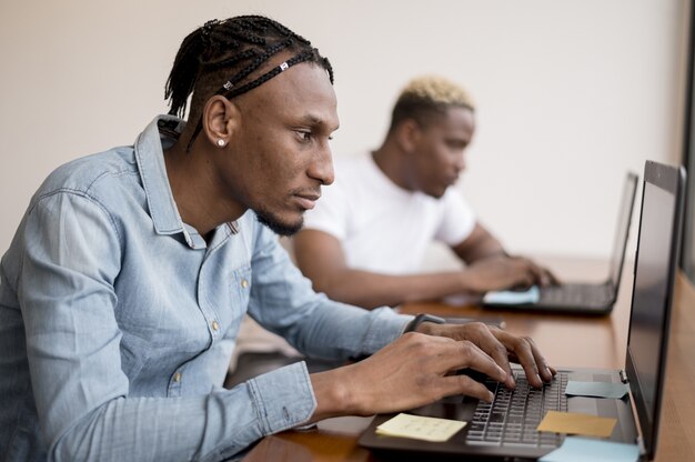 Side view of men working on laptops at the office