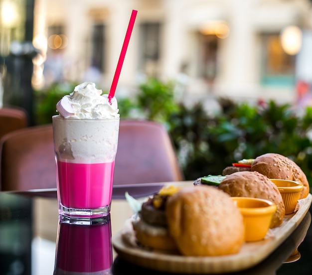 Free photo side view milkshake with whipped cream and burgers