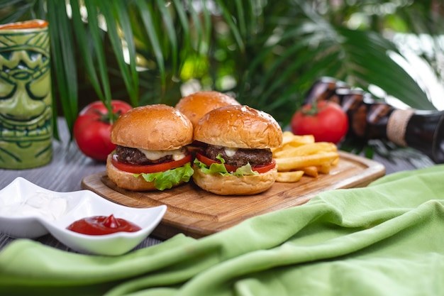 Free photo side view mini burgers beef patty tomato lettuce cheese ketchup and french fries on a board