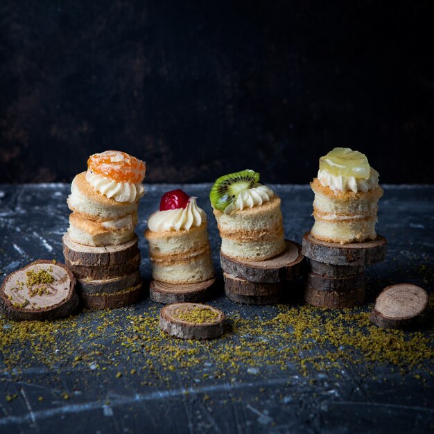 Free photo side view mini cakes with cream and fruits in wood