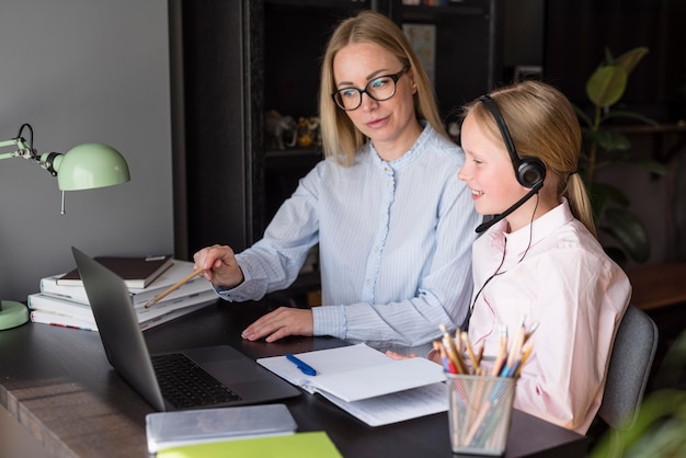 Side view mother and daughter participating at an online class