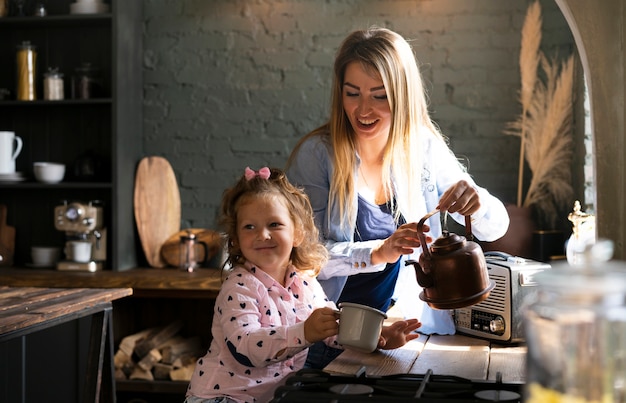 Free photo side view mother pouring tea to daughter