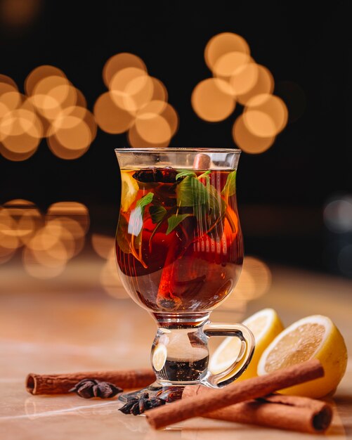 Side view of mulled wine with cinnamon anise and orange in a glass on the table on dark background