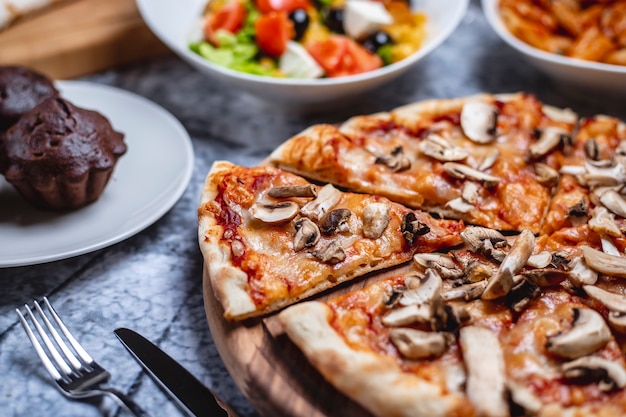 Free photo side view mushroom pizza with tomato sauce cheese salt pepper and champignon on a board