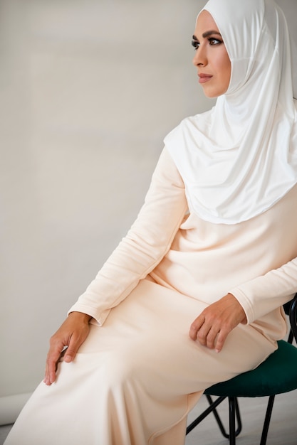 Free photo side view muslim woman posing on chair