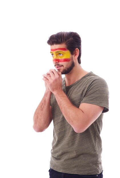 Side view of nervous fan with spain flag on face praying