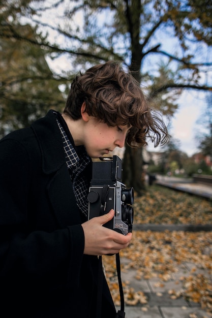 Free photo side view non binary person adjusting a retro camera