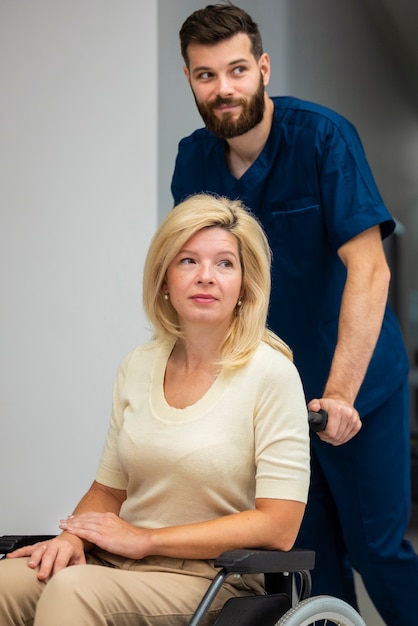 Free photo side view nurse helping patient in wheelchair