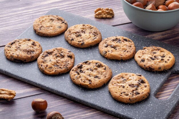 Side view oatmeal cookies with chocolate on a board with nuts