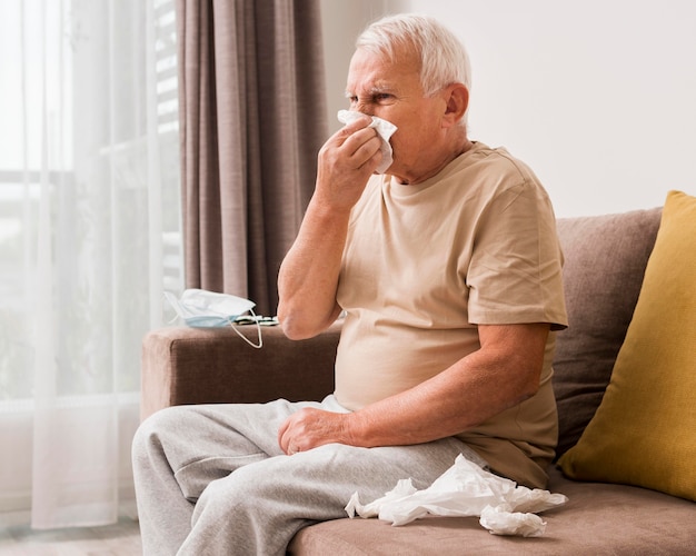 Side view old man blowing his nose