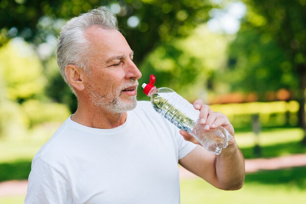 Side view old man drinking water