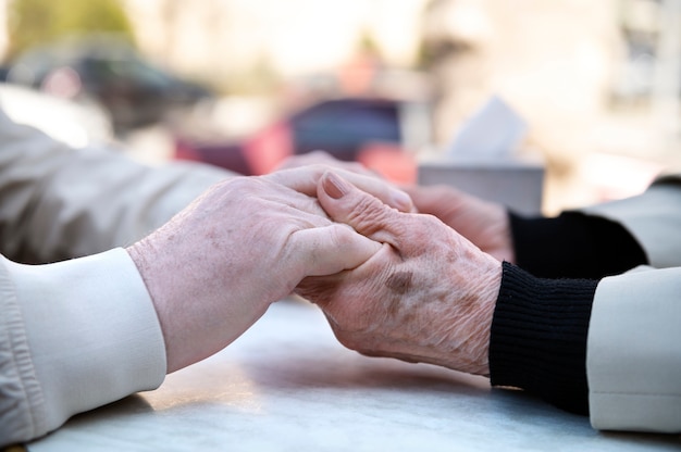 Free photo side view old people holding hands