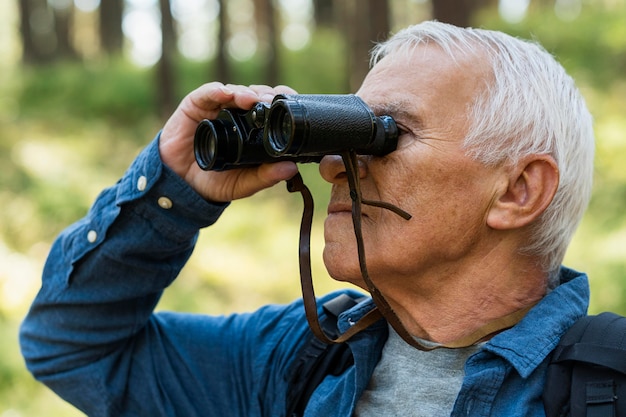 Side view of older man outdoors with binoculars