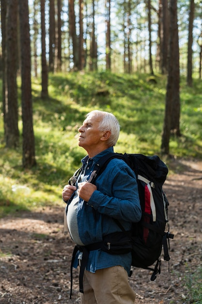 Side view of older man traveling with backpack in nature