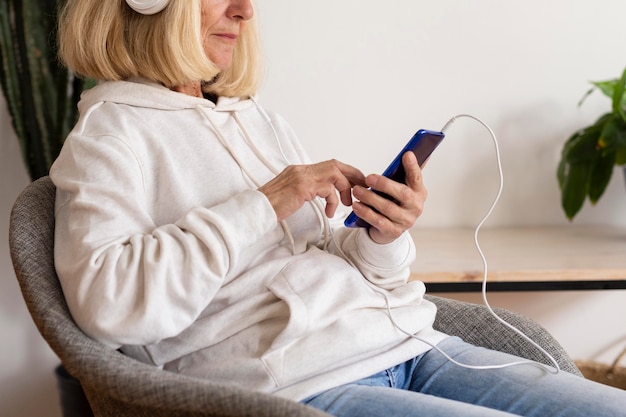 Side view of older woman at home listening to music on headphones