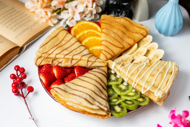 Side view of pancake with fruits and milk chocolate sauce on the table