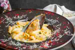 Free photo side view pasta with mussel sauce in round plate