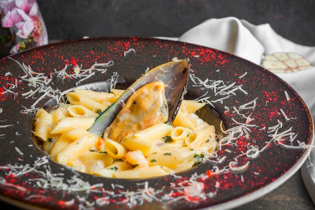 Free Photo side view pasta with mussel sauce in round plate