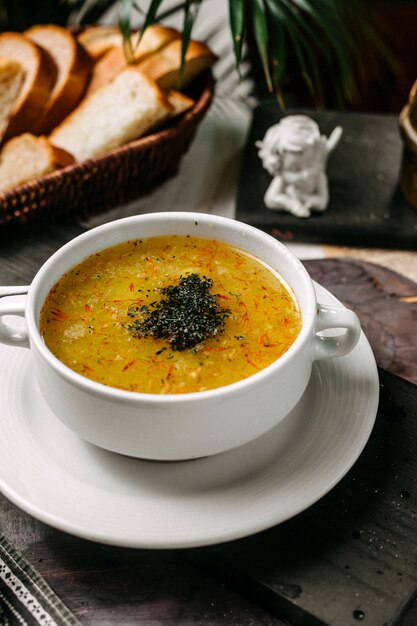 Side view of pea and lentil soup with saffron and herbs in a white bowl