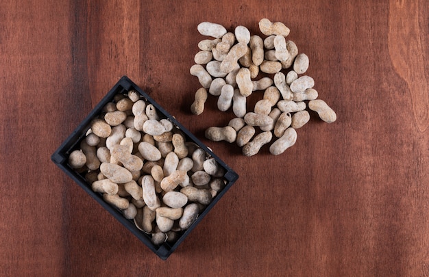 Free photo side view peanuts in box on wooden vertical