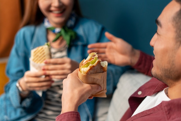 Side view people with paper-wrapped sandwiches