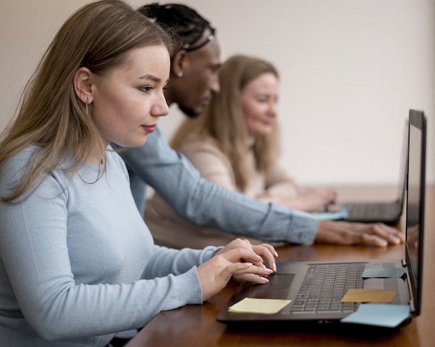 Side view of people working on laptop at the office