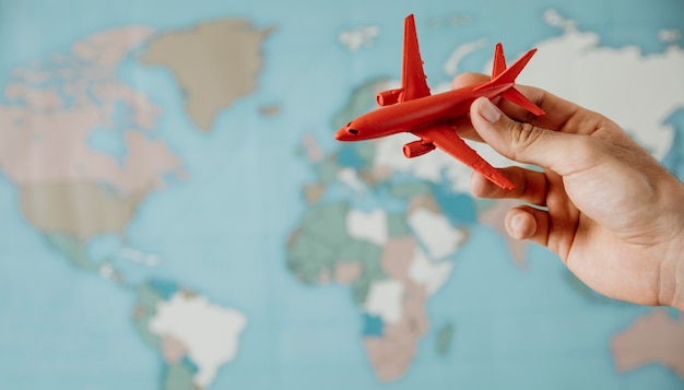 Side view of person holding airplane figurine over map