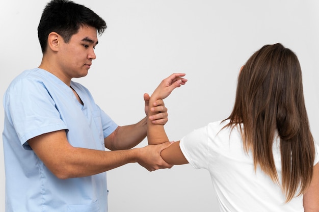 Side view of physiotherapist doing elbow exercises with woman