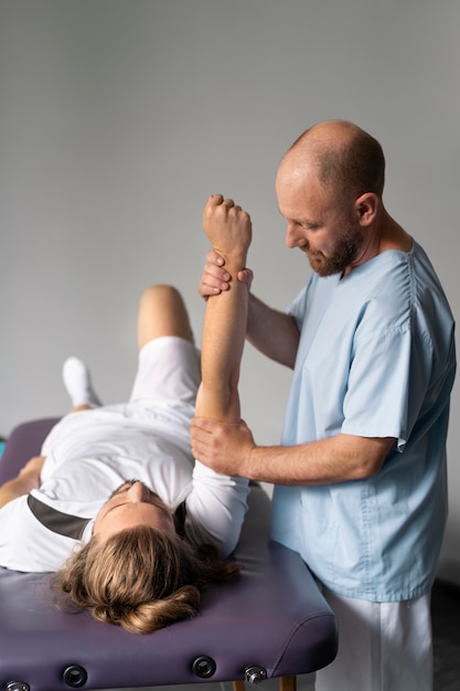 Side view physiotherapist helping patient