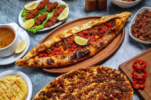 Side view pide with ground meat onion hot pepper slice of lemon and vegetarian steak tartar balls on the table