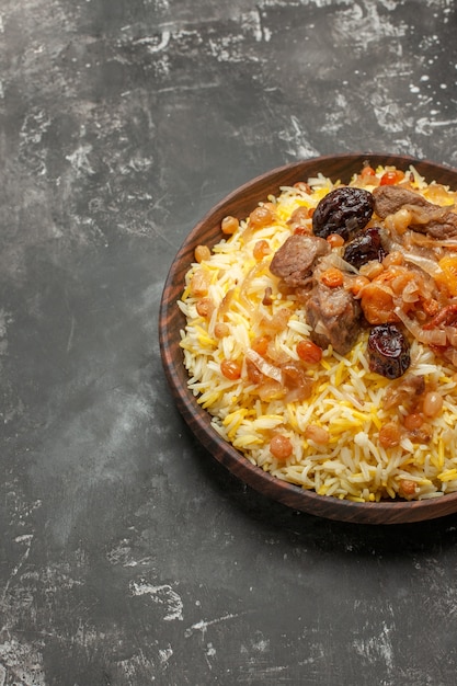 Free photo side view pilaf wooden bowl of an appetizing pilaf on the table